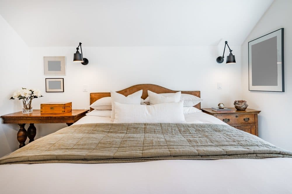 A bedroom with two wall sconces above the bed's night stands