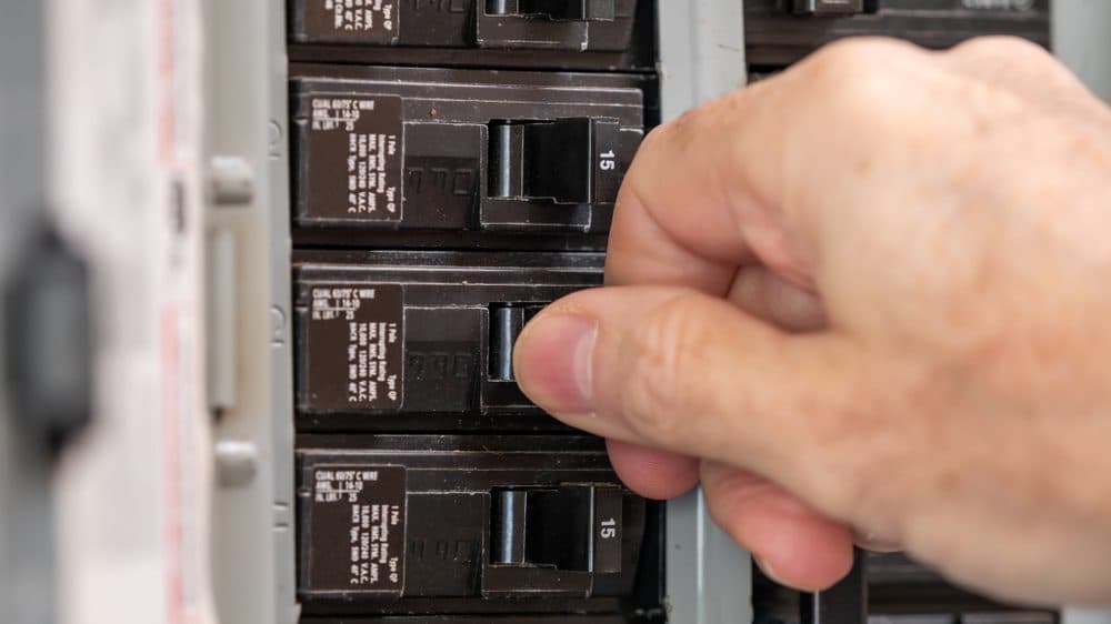 An focused shot of a hand flipping a breaker switch with field of depth blurs