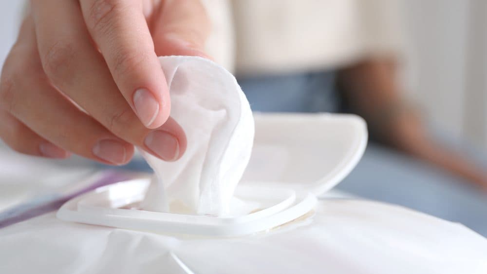 A woman's handing pulling a flushable wipe out of the packaging