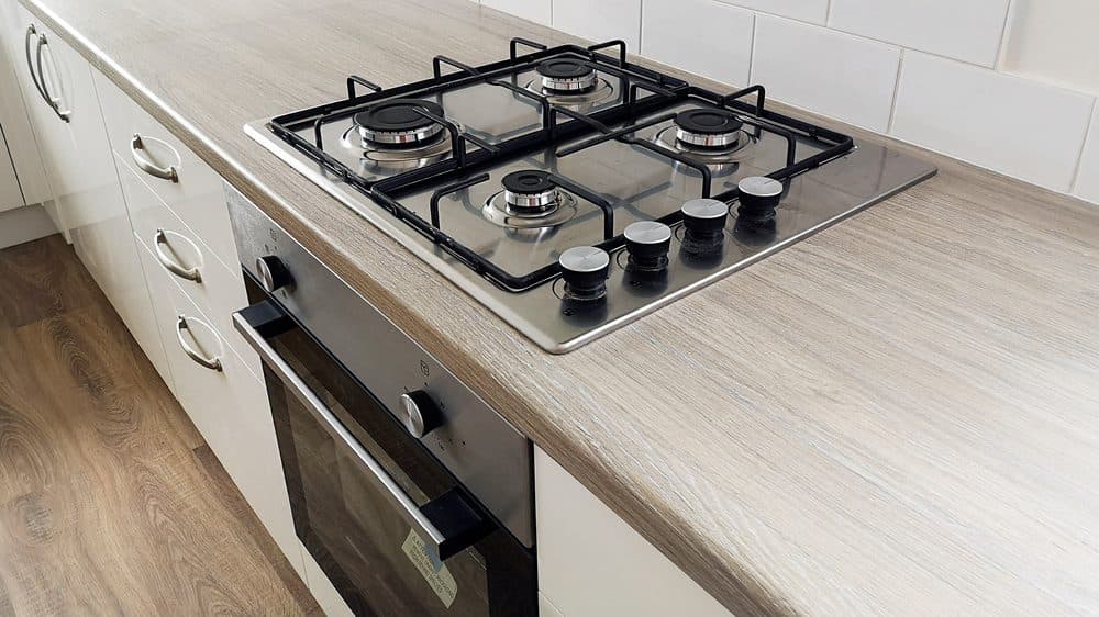 A modern, stainless steel stove and oven combination inside of a sleek kitchen design