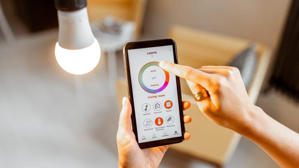 A woman's hand using a phone application to adjust a lightbulb's color temperature
