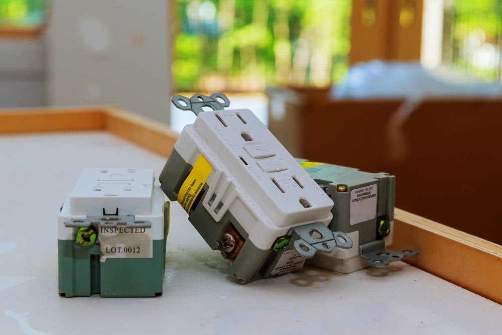 Several three prong electrical outlets sitting on top of a table ready to be installed