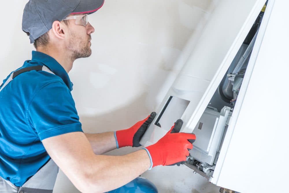 A Horizon technician holding a placing a piece of a furnace back into place while performing maintenance