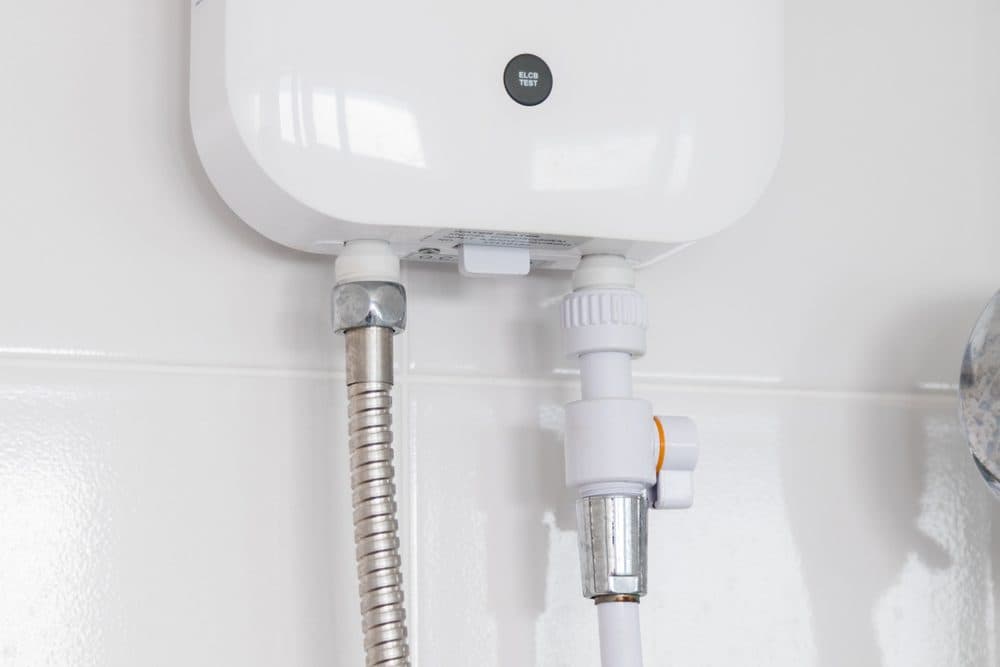 A tankless water heater attached to a white subway tiled wall