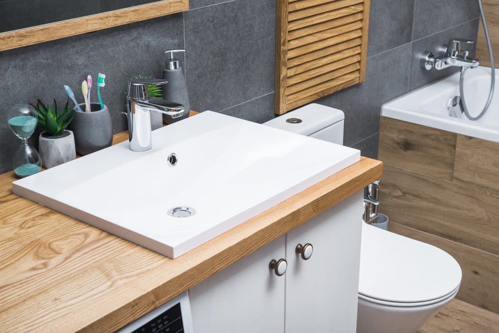 A bathroom with a rectangular faucet that has a leak