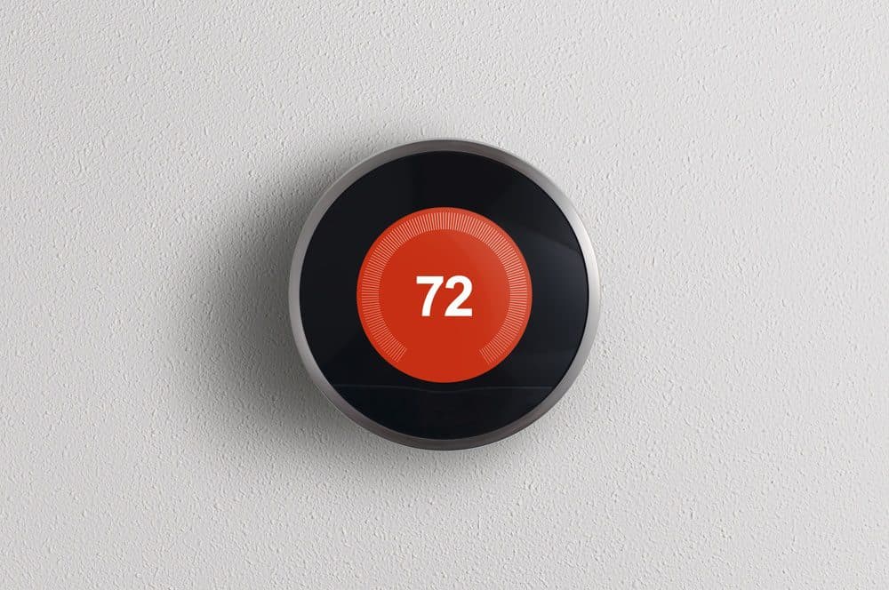 A circular smart thermostat reading 72 degrees inside of a red circle