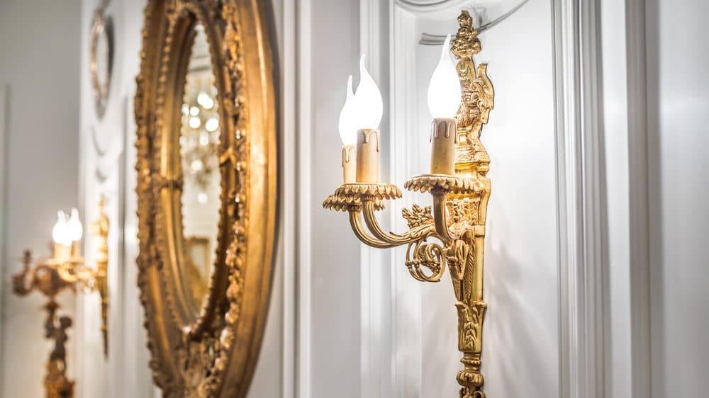 Golden candle sconces surrounding a mirror in a well decorated space