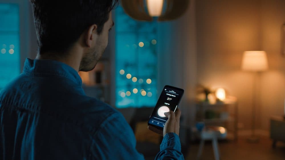 A man in a dark room adjusting his lights using an app on his phone