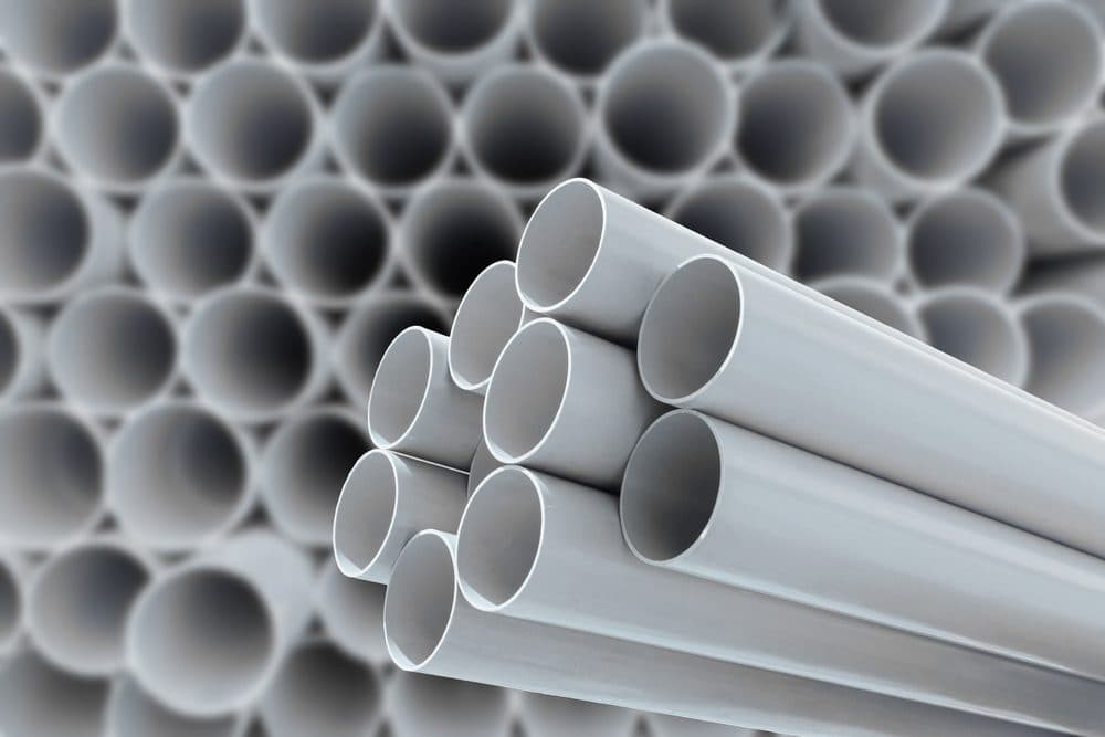 More than 20 polybutylene pipes head on in the background with the focus on 9 foreground pipes at a more horizontal angle