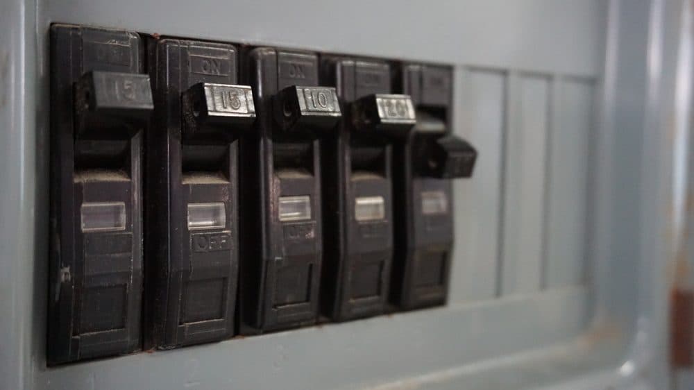 Five circuit breakers in a row with one of them showing signs of needing to be replaced
