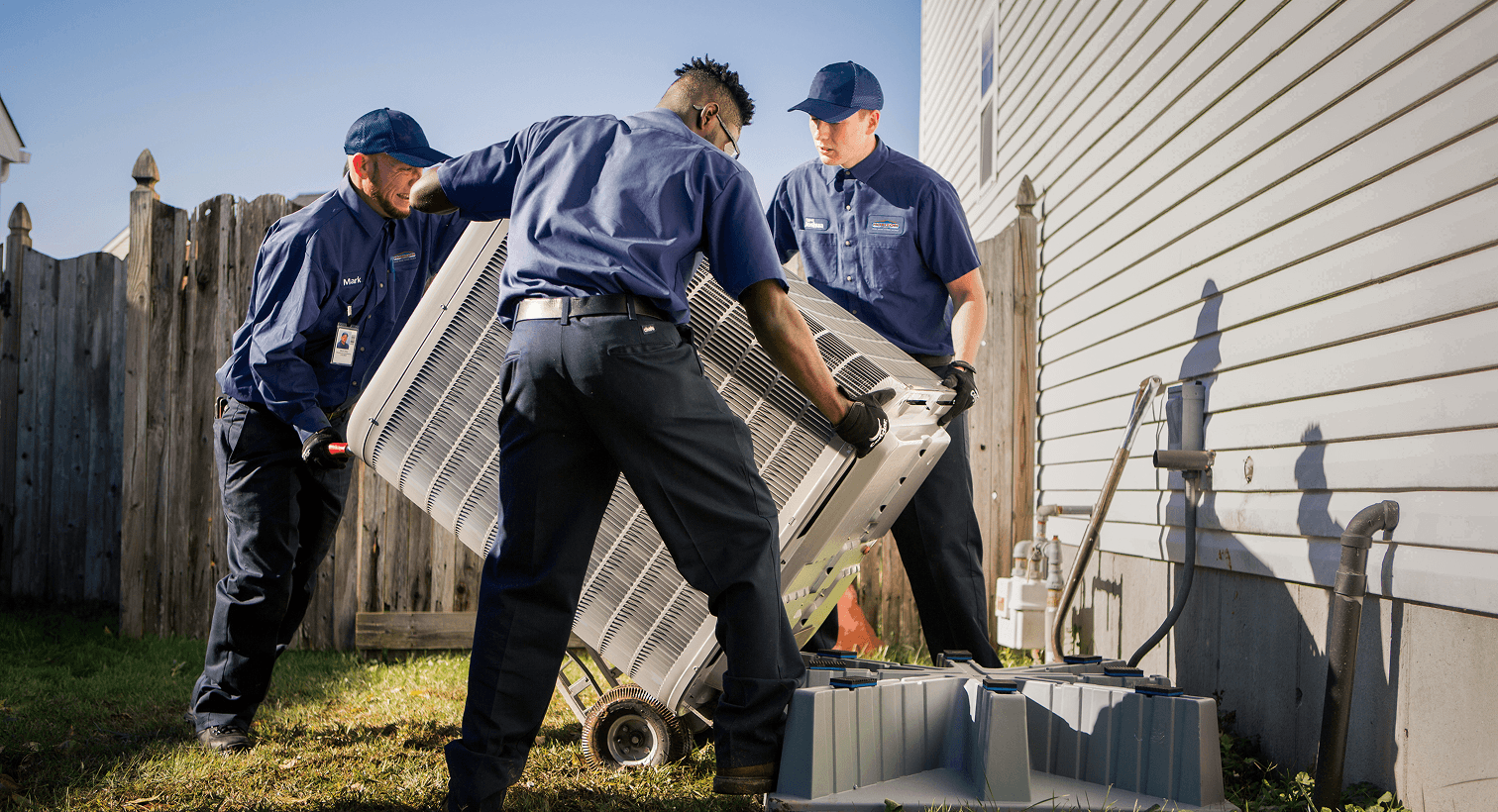 Three men installing an air conditioner